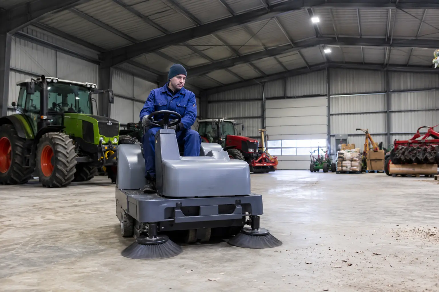Grand hangar agricole, nacelle dépoussiérant la charpente métallique, brosse sur perche nettoyant une plaque translucide
